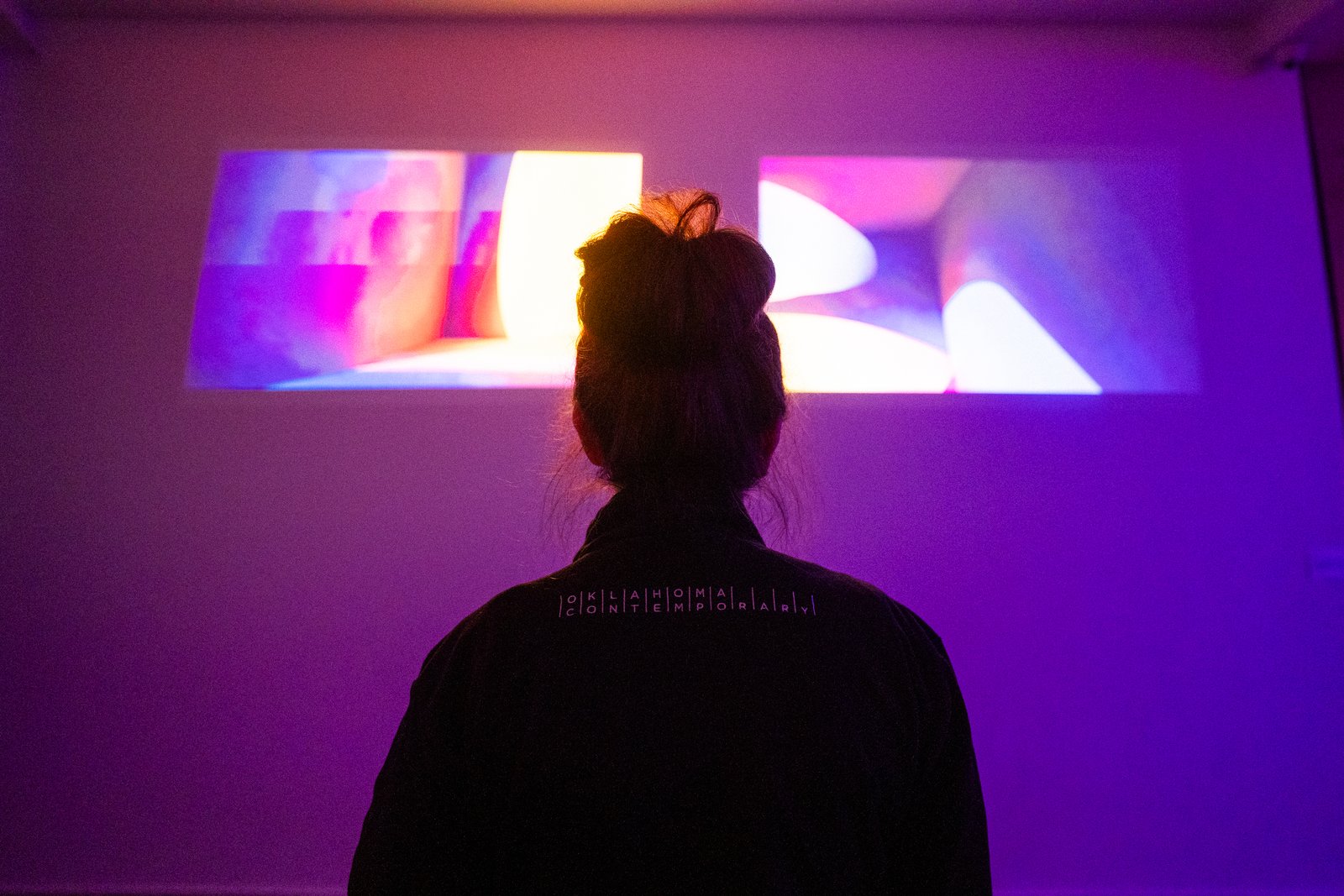 A visitor stands before the two projected image fields of Lumaform.