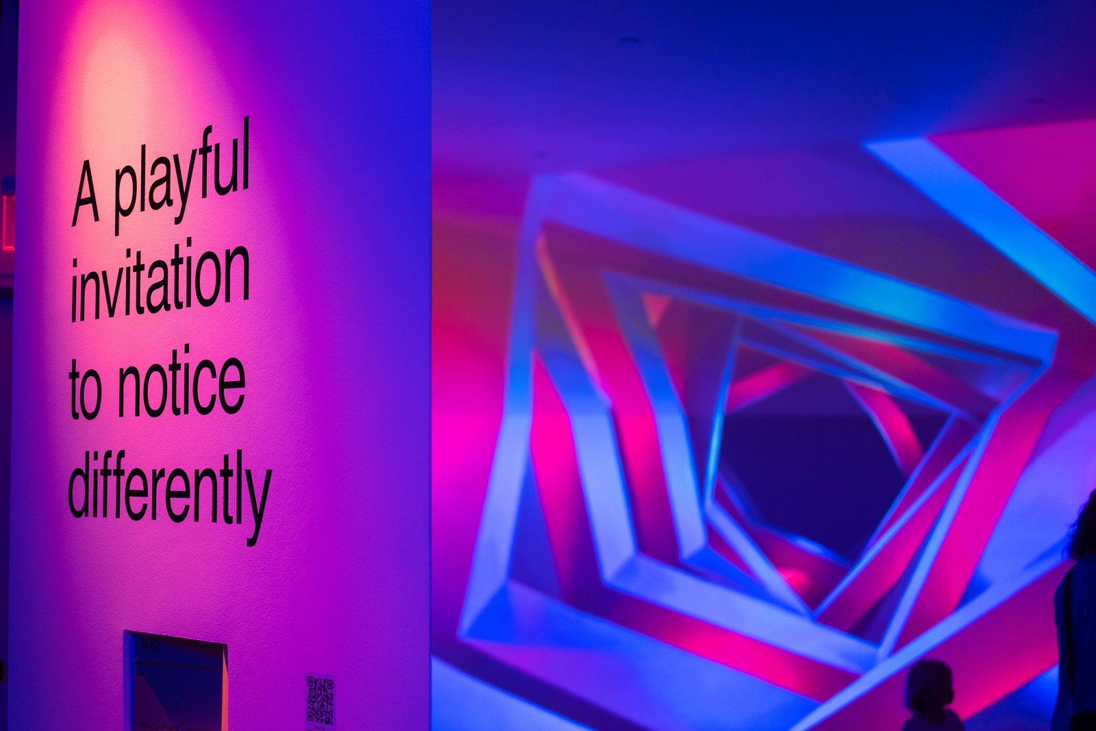 Portal Field casts blue and magenta geometric light beside the wall text, ‘A playful invitation to notice differently.’