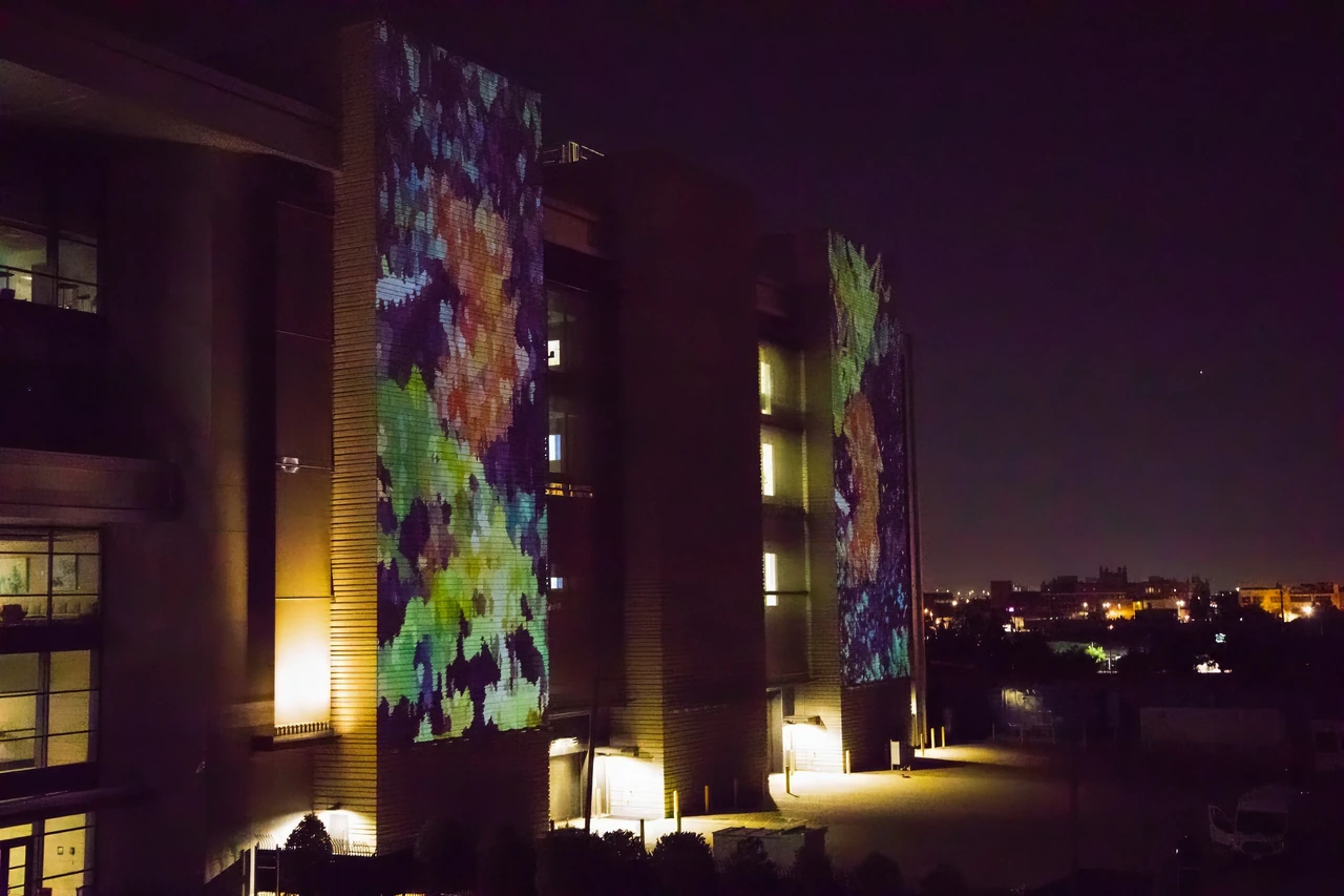 Two illuminated OSU Discovery façades show colorful Butterfly Portals projections at night.